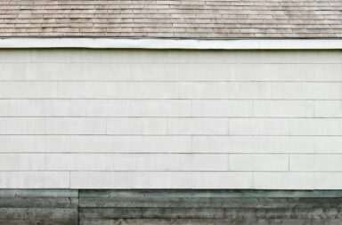 A minimalist exterior wall with white siding and a shingled roof, showcasing clean lines and simplicity.