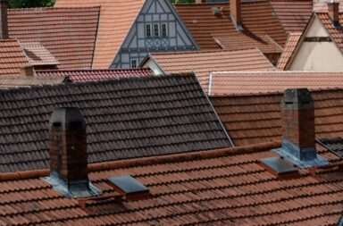 a row of rooftops with a clock tower in the background